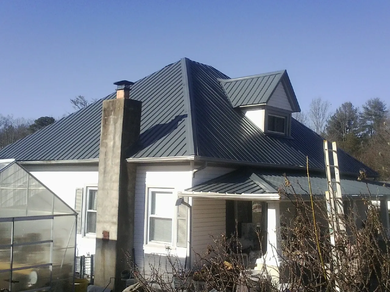 Dark blue standing seam metal roof on a white farmhouse with dormer — Slate & Tile Roof Repair by Roofing Brothers in La Palma