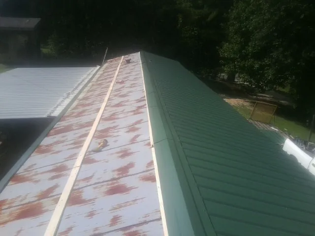 Old rusted panels beside newly installed green metal roofing — Wind Damage Roof Repair by Roofing Brothers in La Palma