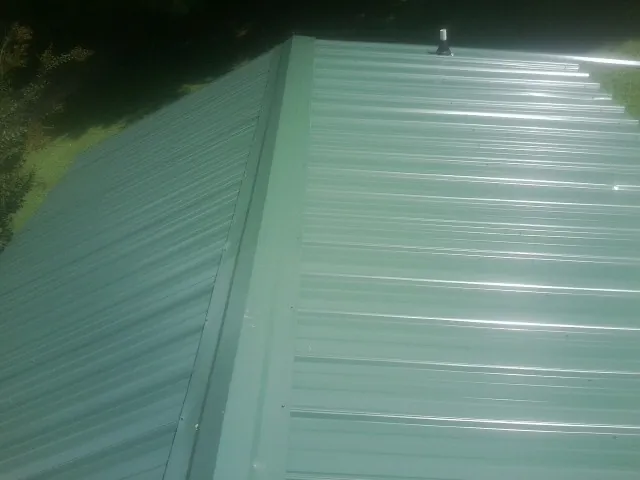 New green metal panels meeting at the ridge of a roof — Flat Roof Repair work by our crew in La Palma