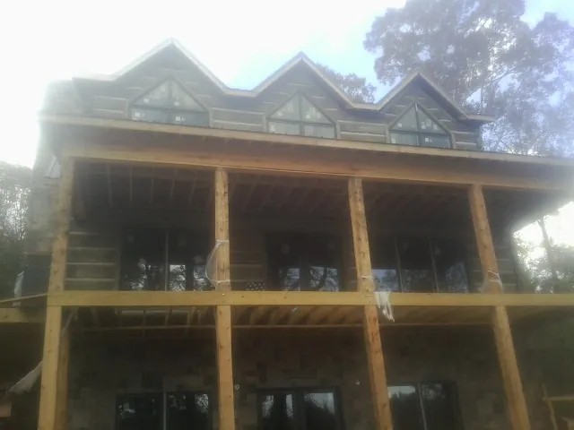 Dormers and porch framing on a large log home under construction — Roof Coating work by our crew in La Palma
