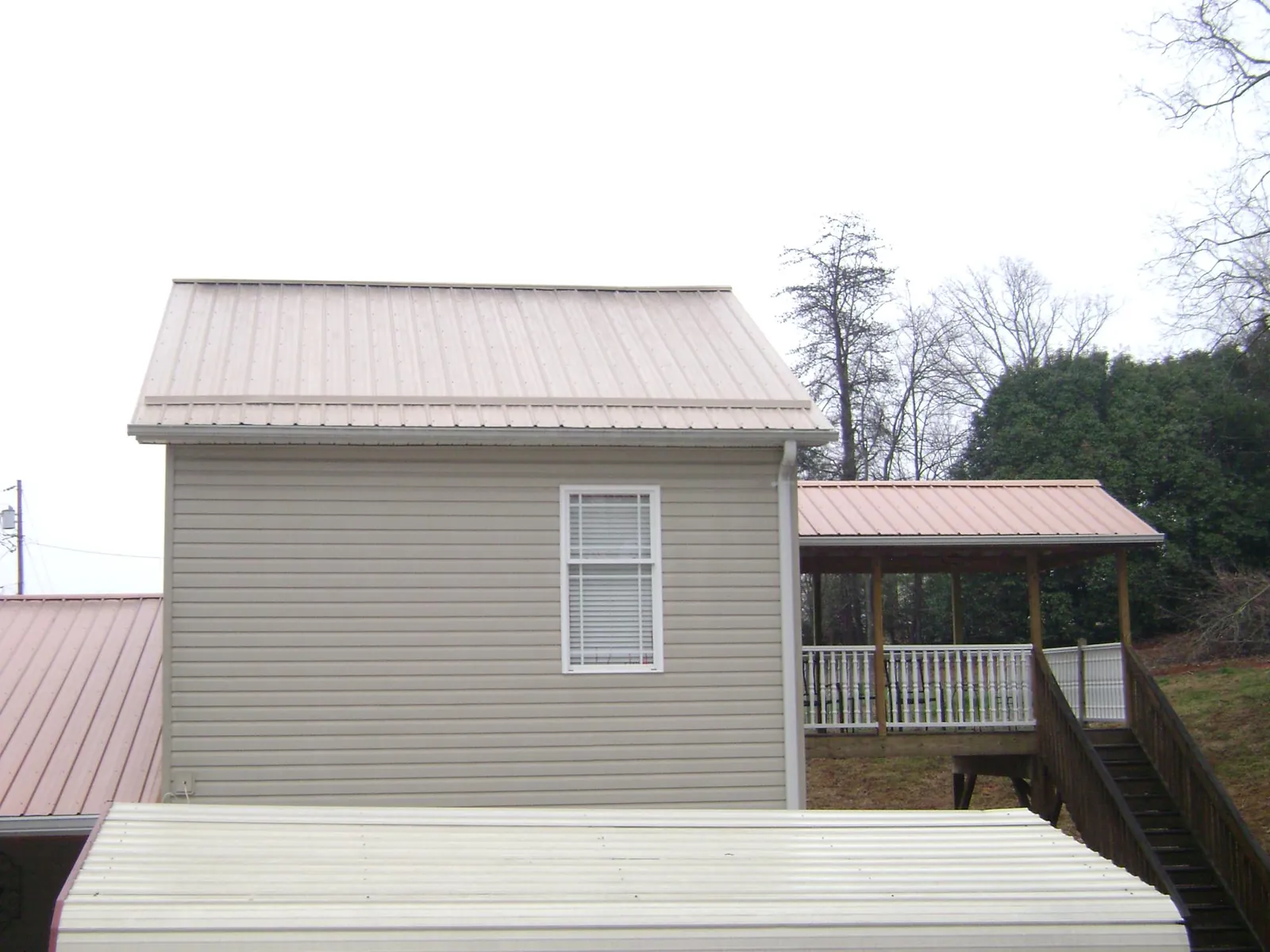 Tan metal roofs on a two story addition and attached porch, from a Roof Replacement job in La Palma