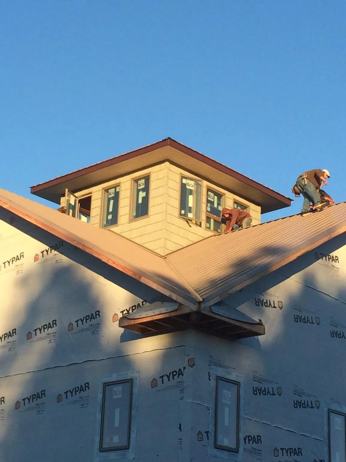 Roofers working around a rooftop cupola on a new metal roof at sunset — Roof Waterproofing in La Palma by Roofing Brothers